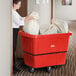 A woman pushing a large white bag into a red Lavex cube truck.