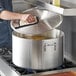 A man holding a large Choice aluminum sauce pot with a lid.