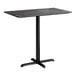 A rectangular bar height table with a smooth dark finish and a black cross base plate.