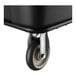 A close-up of a caster wheel attached to the bottom of a black utility cube truck.
