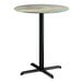 A round bar height table with a textured canyon painted faux metal finish top and a black cross base plate.