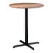 A round bar height table with a textured farmhouse finish top and a black cross base plate.