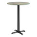 A round bar height table with a textured canyon painted faux metal finish top and a black cross base plate.