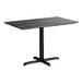 A rectangular standard height table with a smooth black finish and a cross base plate.