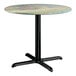 A round standard height table with a textured canyon painted faux metal finish top and a black cross base plate.