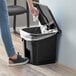 A person using their foot to open a Lavex rectangular step-on trash can.
