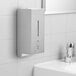 A silver Bobrick stainless steel automatic soap dispenser on a white tile wall.
