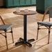 A round standard height table with a textured farmhouse finish and a black cross base plate.