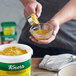 A person pouring Knorr Caldo de Pollo yellow powder into a bowl.