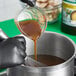 A person pouring brown Knorr Ultimate Liquid Concentrated Vegetable Base into a pot.