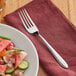 An Acopa Remy stainless steel salad fork on a plate of fruit and vegetables.