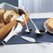 A tray of sliced bread with Acopa stainless steel serving utensils.