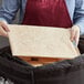 A woman using a Vesture Cordless Heating Element in a black delivery bag with a white cloth around it to keep food warm on a table.