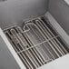 A metal rack inside a box with several metal utensils in it.