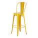 A yellow metal barstool with a backrest.