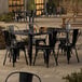 A Lancaster Table & Seating black table with six chairs on an outdoor patio.