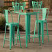 A Lancaster Table & Seating aquamarine bar height outdoor table with two green metal barstools.