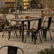 A Lancaster Table & Seating distressed copper outdoor table with chairs on a patio.