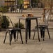 A Lancaster Table & Seating outdoor table with two black chairs on a patio.