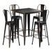 A Lancaster Table & Seating distressed copper bar table with 4 black metal barstools.