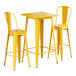 A Lancaster Table & Seating yellow metal bar table with two chairs.