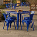 A blue metal Lancaster Table & Seating outdoor table with four chairs on a stone patio.