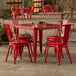 A Lancaster Table & Seating ruby red table with 4 chairs on a patio.