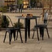 A Lancaster Table & Seating onyx black metal table and chairs outside on a patio.