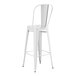 A white metal bar height table with 4 white chairs with backrests.