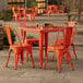 An orange metal Lancaster Table & Seating outdoor table with chairs.