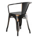 A black metal arm chair with a black seat and back on a Lancaster Table & Seating distressed copper table.