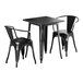 A Lancaster Table & Seating black metal table with two chairs on an outdoor patio.