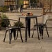 A Lancaster Table & Seating black metal table and chairs on an outdoor patio.