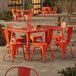 A Lancaster Table & Seating outdoor table with orange chairs on a patio.