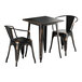 A black square Lancaster Table & Seating outdoor table with brown edges and two black metal chairs.