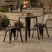 A Lancaster Table & Seating distressed copper table and chairs outside on a patio.