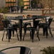 A Lancaster Table & Seating Onyx Black outdoor table with chairs on a patio.