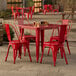 A red metal Lancaster Table & Seating outdoor table with chairs.