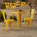 A Lancaster Table & Seating citrine yellow table with chairs on an outdoor patio.