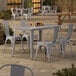 A Lancaster Table & Seating outdoor table and chairs with metal legs on a patio.