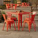 An orange metal table and chairs on a stone patio.