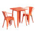 An orange metal Lancaster Table & Seating outdoor table with two arm chairs.