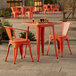 A Lancaster Table & Seating amber orange table and chairs on an outdoor patio.