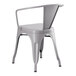 A Lancaster Table & Seating nickel gray metal chair with armrests at an outdoor table.