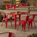 A red Lancaster Table & Seating outdoor table with chairs on a patio.