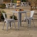 A Lancaster Table & Seating outdoor table with two gray chairs on a patio.