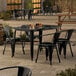 A Lancaster Table & Seating Onyx Black outdoor table with 4 chairs set on a patio.