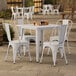 A Lancaster Table & Seating white table with four white chairs on an outdoor patio.
