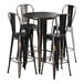 A Lancaster Table & Seating distressed copper bar height table with four black metal chairs.