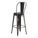 A black metal bar stool with a backrest at a table.